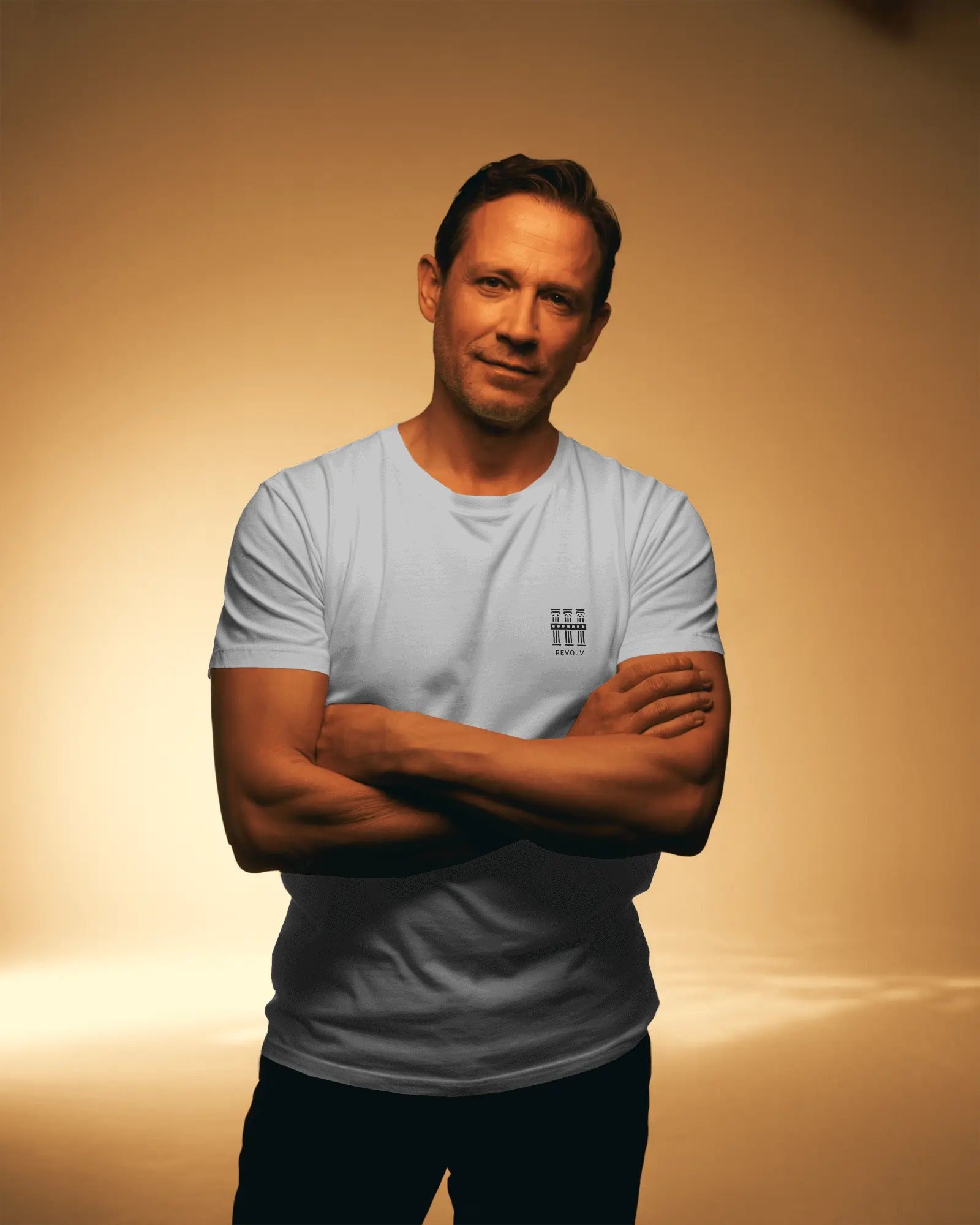 Man wearing a light white t-shirt with a logo on a beige background